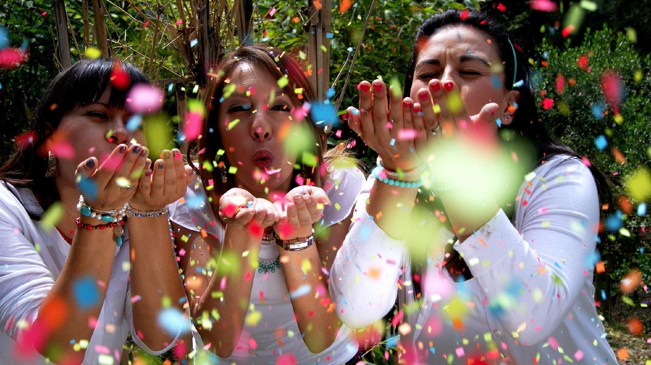Drie vrouwen die samen plezier hebben met confetti, symbool voor verbinding, lichtheid en herstel door lichaamsgerichte psychotherapie